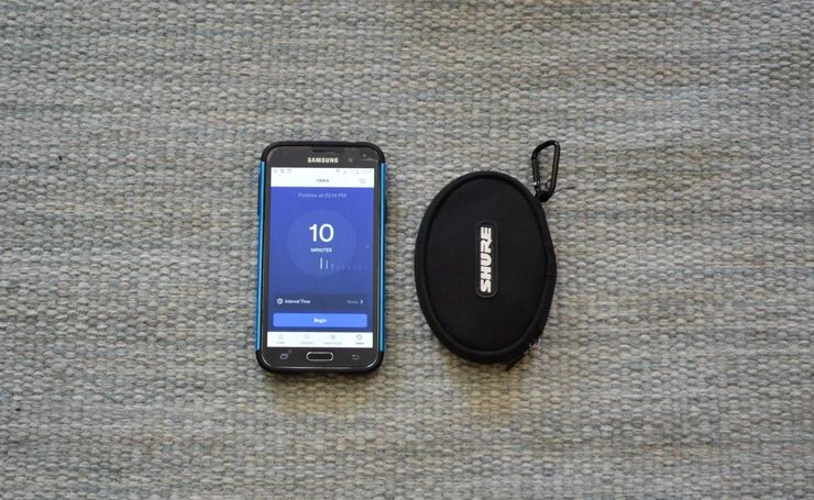 Phone showing a meditation timer next to a Shure earbud case