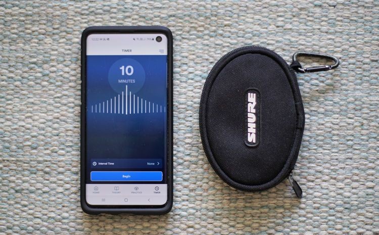 Phone showing a 10-minute meditation timer next to a Shure earbud case